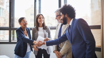 Four people are shaking hands, two men, two women