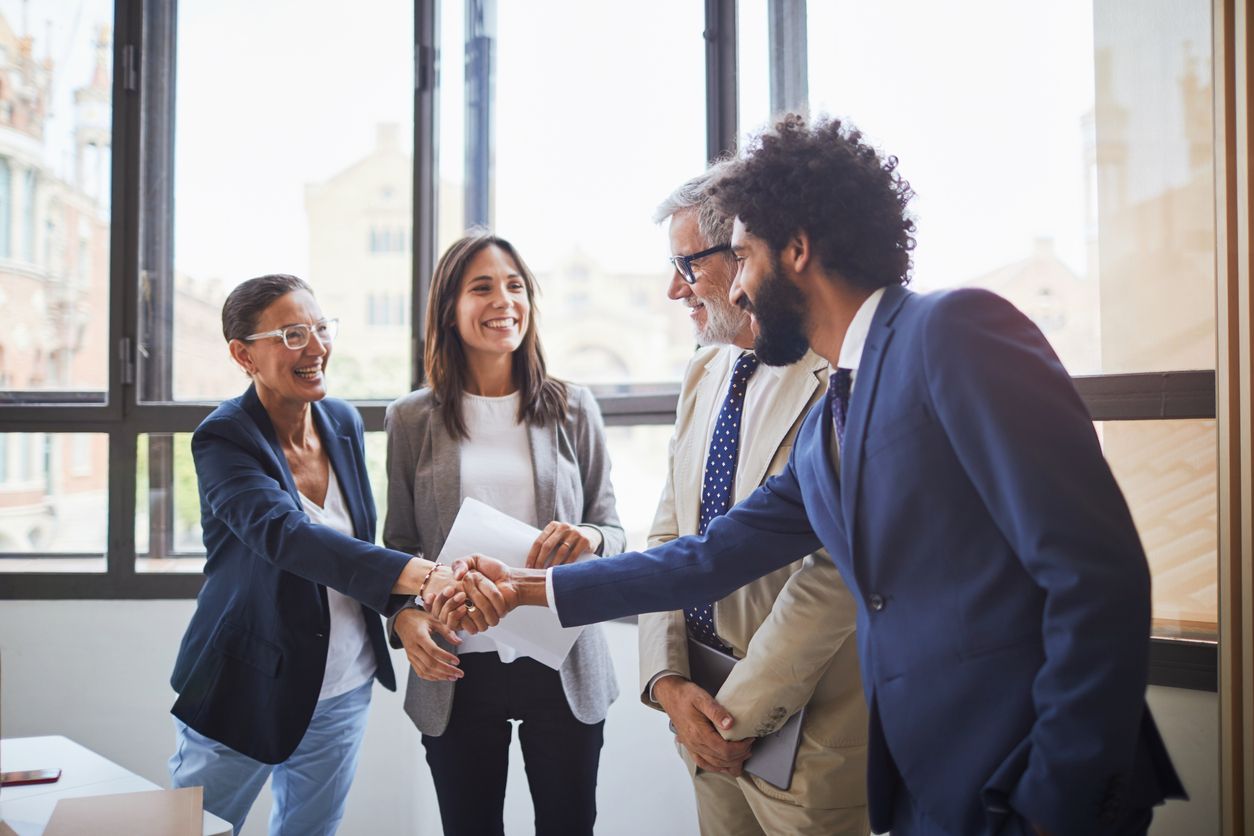 Four people are shaking hands, two men, two women